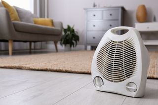 An electric fan heater on the floor of a living room