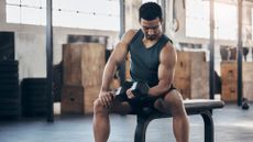 Man doing a dumbbell curl sat on weight bench