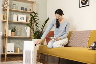 Do air purifiers help with dust? Woman using air purifier in her home