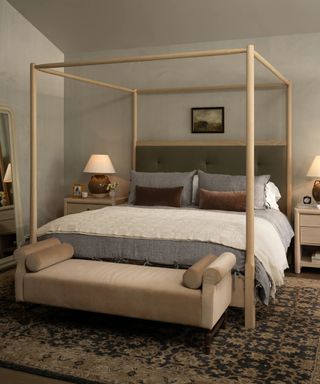 farmhouse style bedroom with a pale wood canopy bed and a large vintage style rug designed by mcgee and co