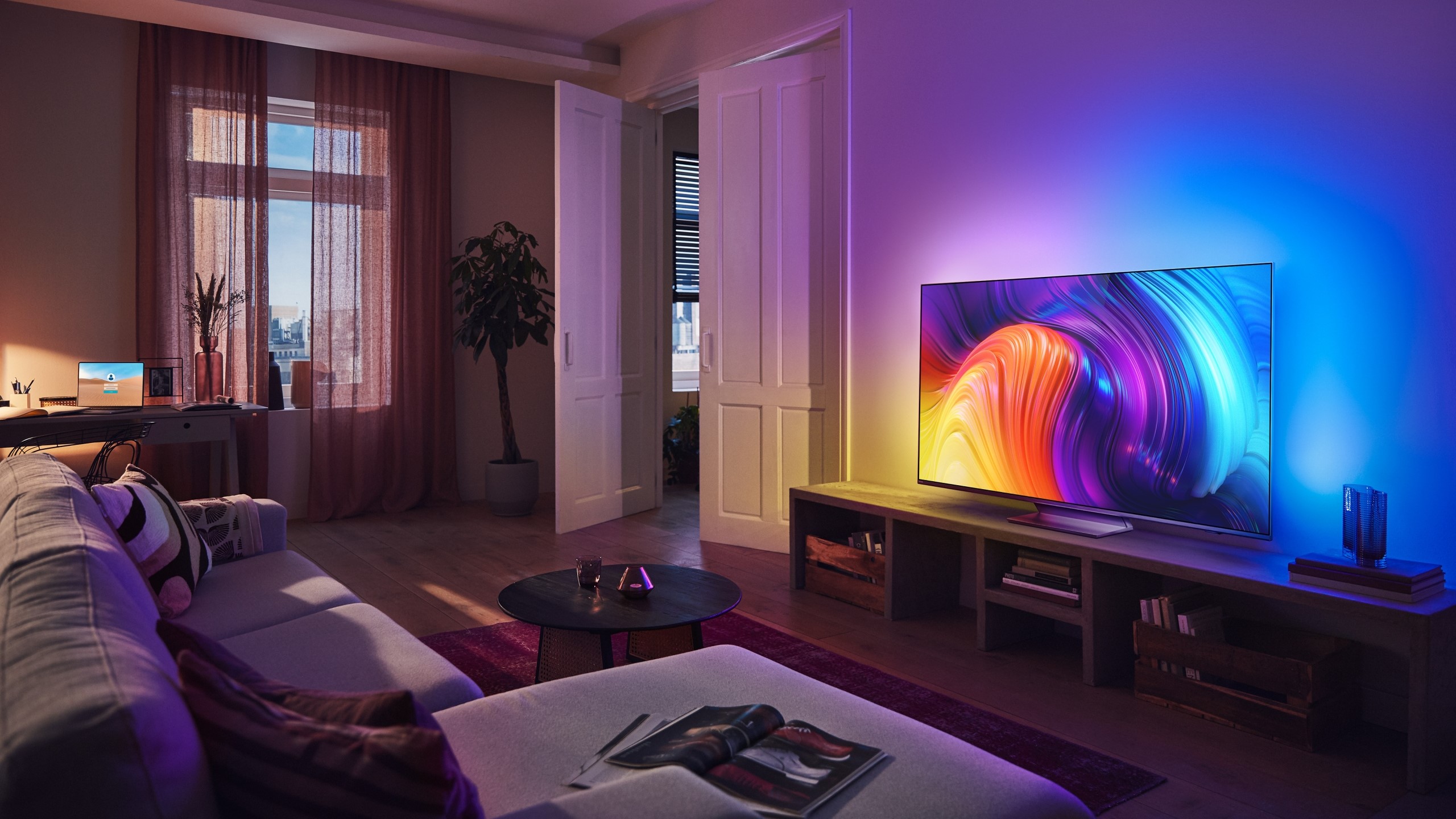 The Philips OLED807 on display in a living room - the wall behind it is light up by the Ambilight feature