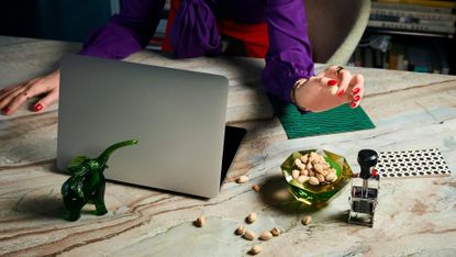 Desk with open computer and office essentials, plus bowl of nuts and a glass ornament