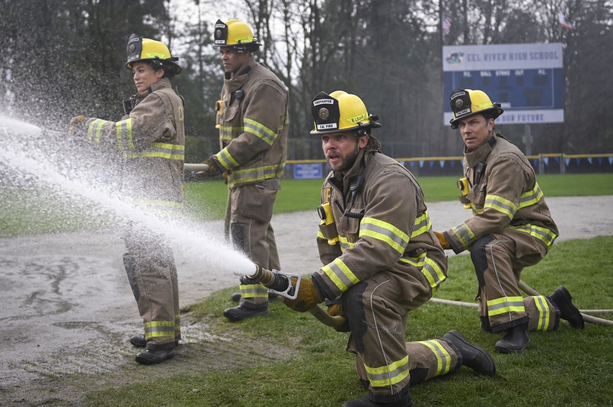 From left to right: Gabriela and a man holding up a fire hose and Bode and Luke kneeling while holding up another fire hose. 