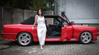 Canon EOS R1 sample image: a female model posing with a red BMW