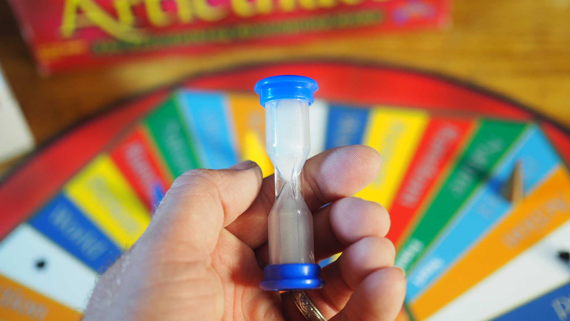 A hand holds the articulated sand timer