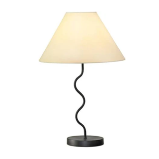 A white lampshade on a black squiggle base
