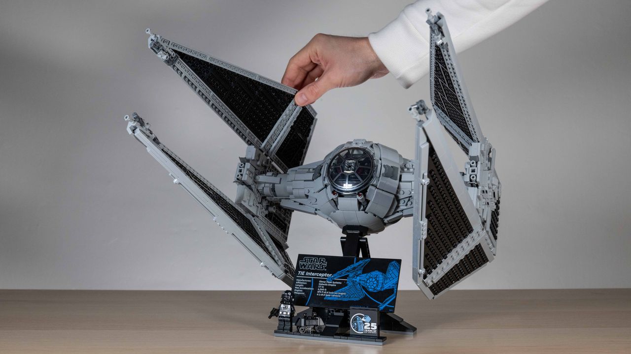 Lego TIE Interceptor, 3/4 view on a neutral background with hand lifting up hinged wing