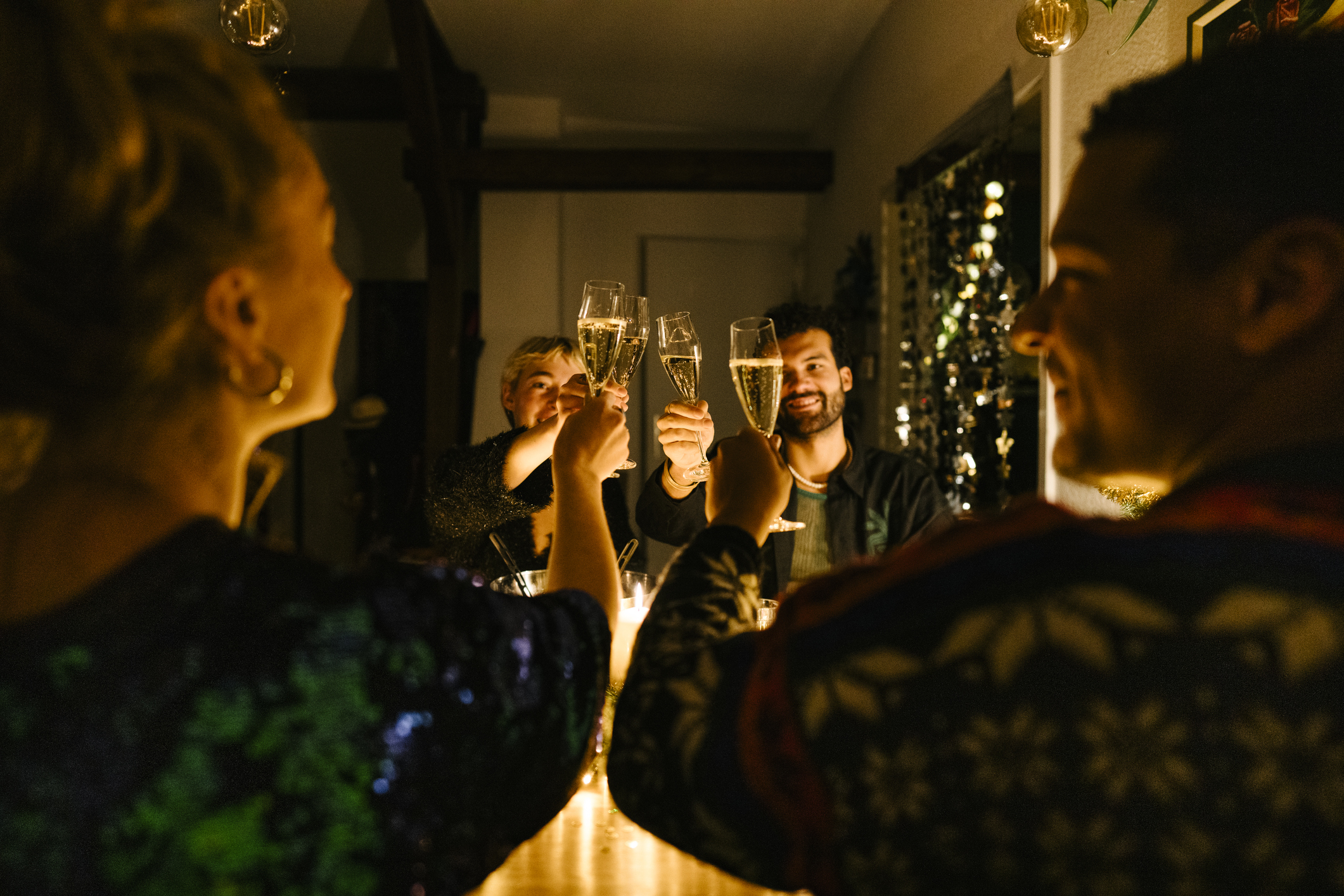 Four adults toasting New Year&#039;s Eve with champagne.