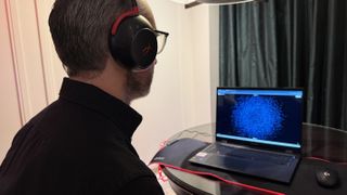 The HyperX Neurable prototype worn by a man, who is looking at a laptop with a cloud of dots on it