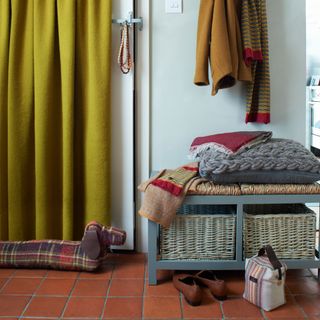 Front door covered in mustard door curtains with a tartan dog draught excluder on the floor