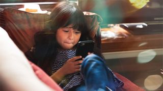 Girl seated comfortably in the living room on the sofa using smartphone