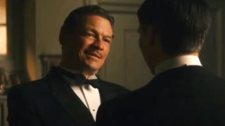 Dominic West stands speaking in front of Robert James-Collier in Downton Abbey: A New Era.