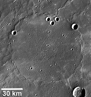 This Messenger photo of Mercury shows wrinkle ridges around a network of troughs that formed when the volcanic plains were stretched apart. The wrinkle-ridge ring, about 100 km in diameter, is formed over the rim of a so-called ghost crater.