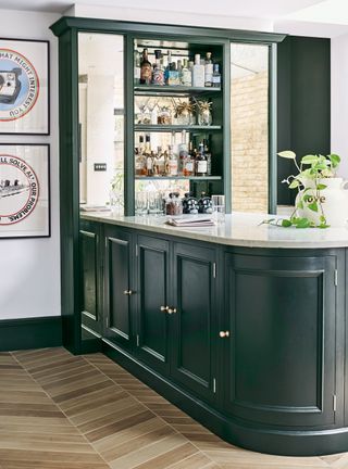 Home bar with island painted green and wood floor