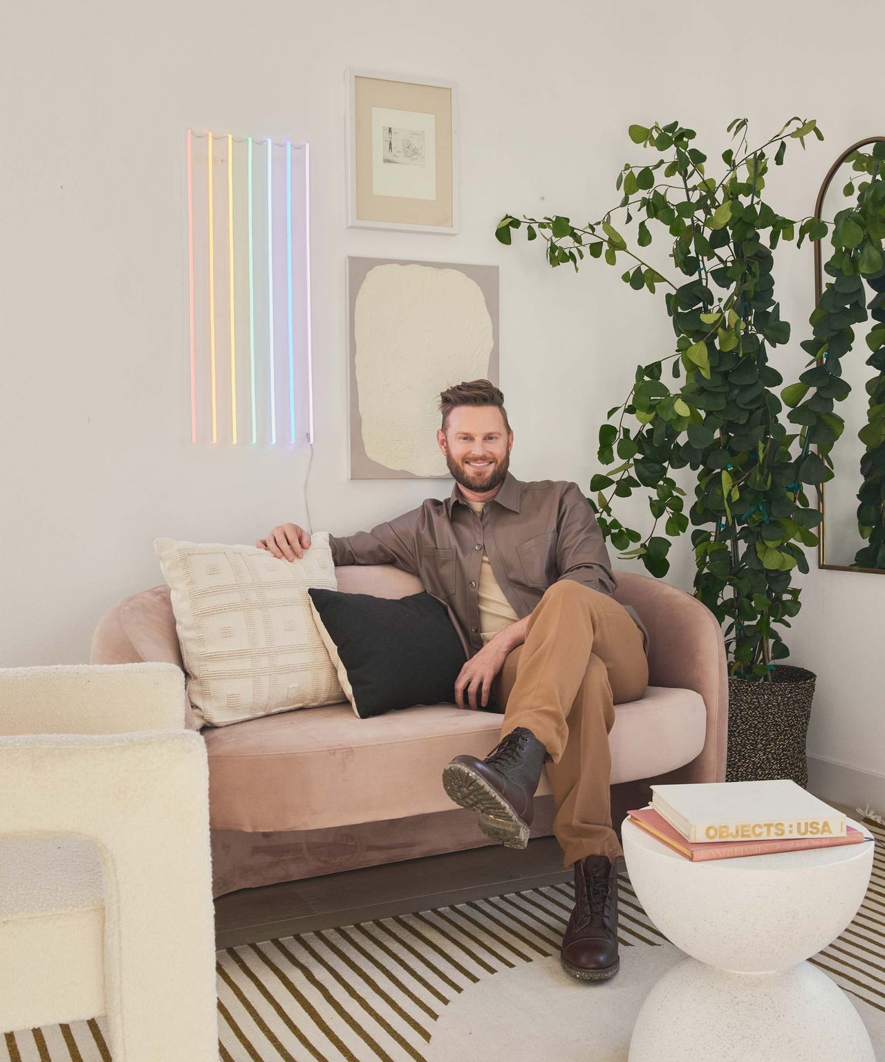 Eye interior designer Bobby Burke sitting in the living area with neon lights by Yellowpop