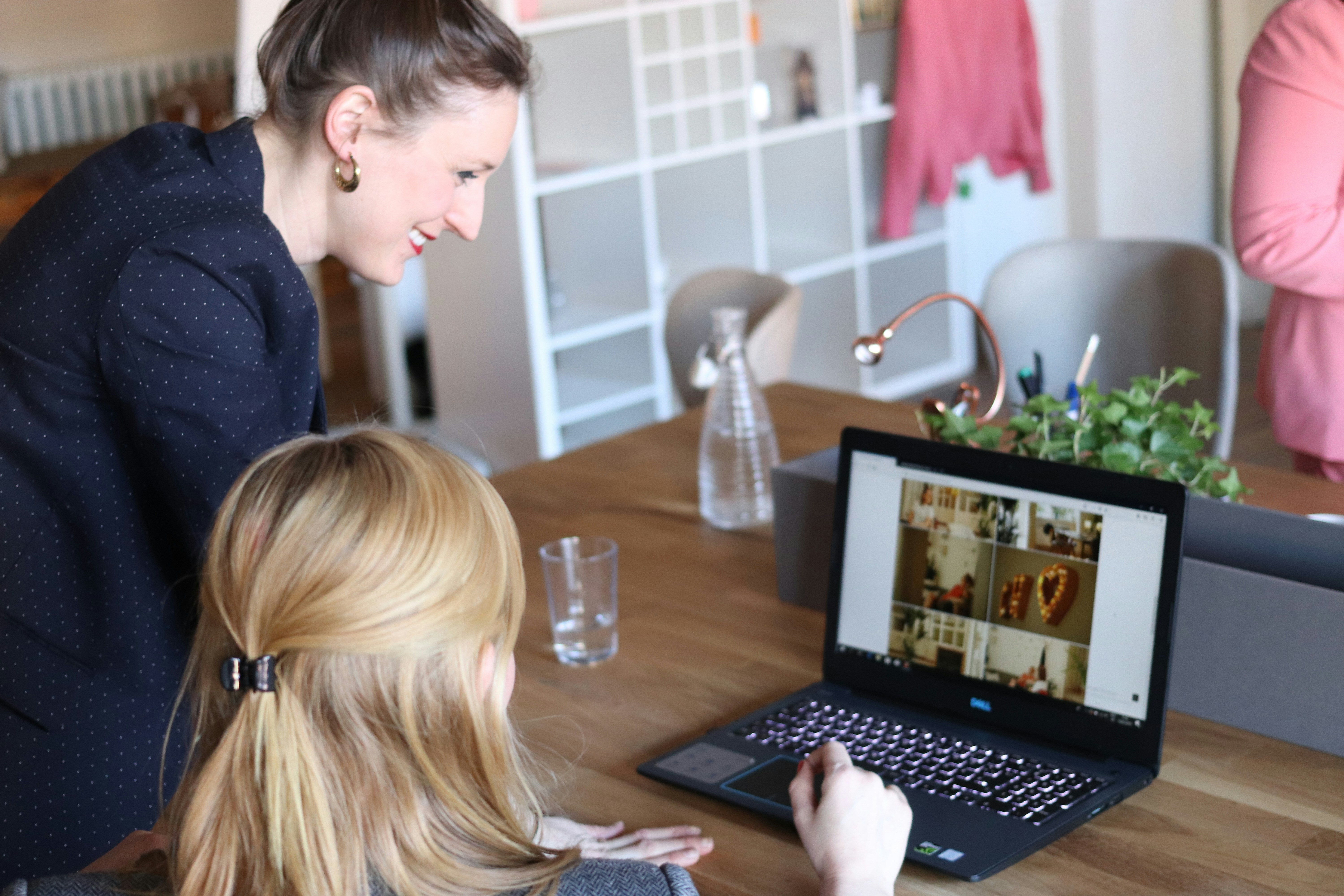 Lagerfotos von Menschen, die lächeln und Laptops in einem kleinen Geschäftsumfeld betrachten.