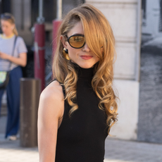 a woman with curly brown hair wearing a black sleeveless top