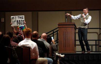 White nationalist leader Richard Spencer speaks on the Texas A&M University campus as a silent protester holds a placard in College Station, Texas.