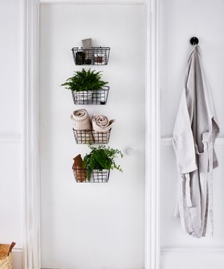 Black wire storage baskets hung from back of bathroom to door to keep bathroom essentials