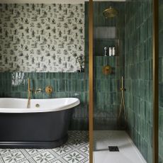 bathroom with green wall tiles, freestanding bath and gold shower