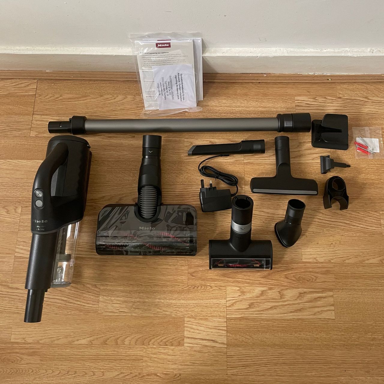 Miele DuoFlex HX1 components laid out on wooden flooring