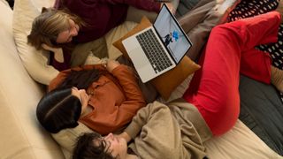 Three people on a couch view a video on the Apple MacBook Air M4