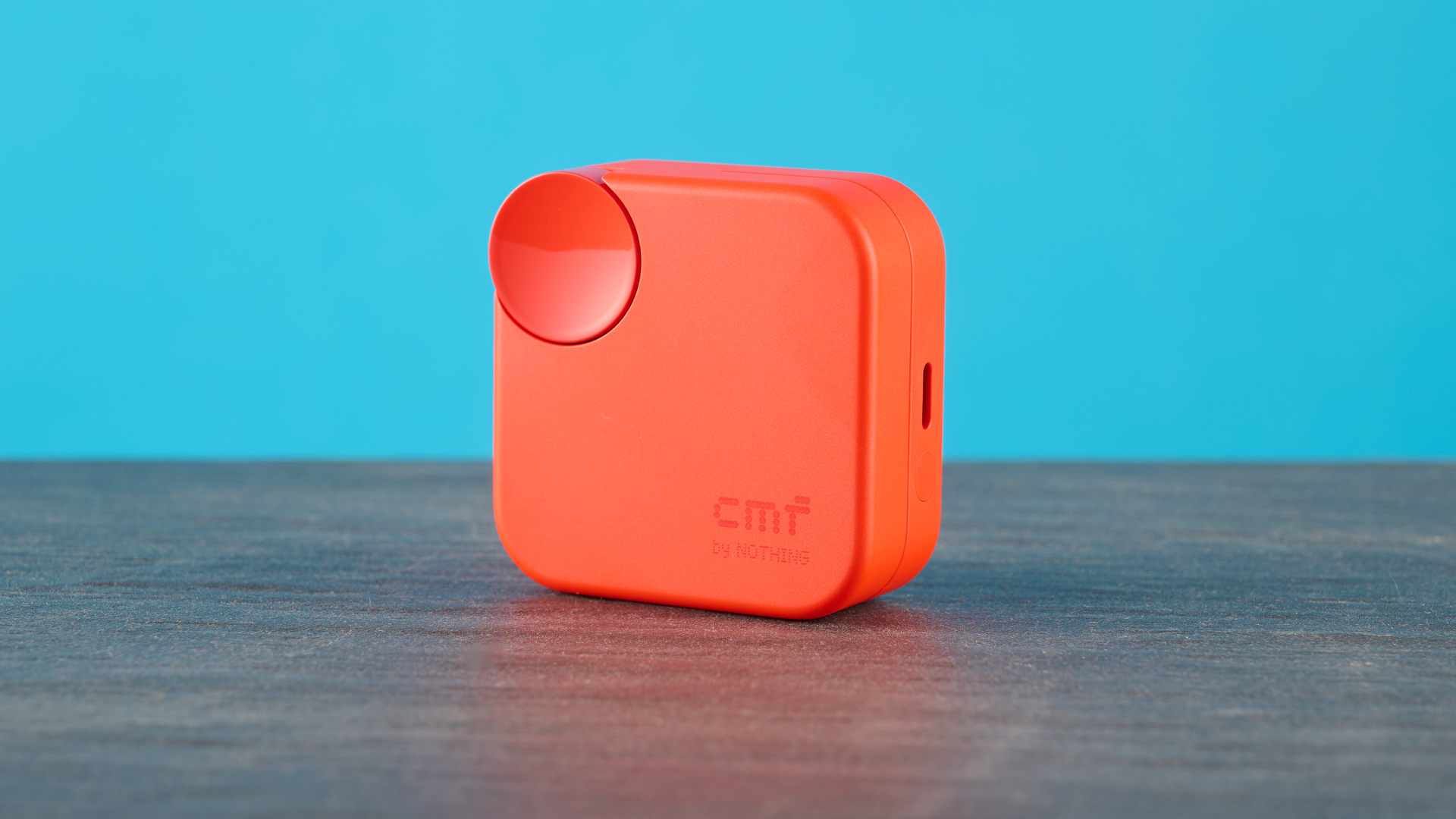 cmf buds 2a in the orange colorway photographed in front of a blue background