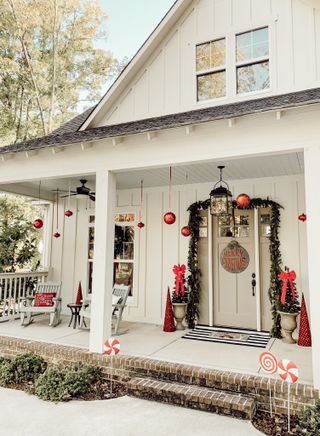 a white painted porch decorated with red baubles and foliage for Christmas holidays