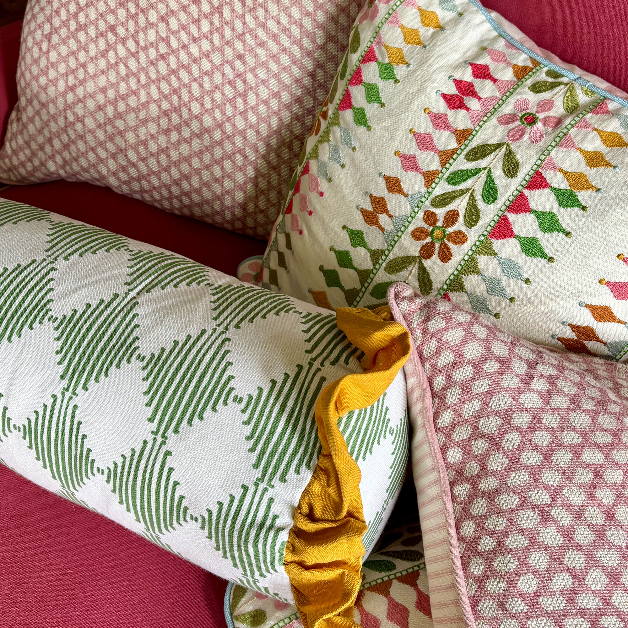 Pile of colourful patterned square and bolster cushion