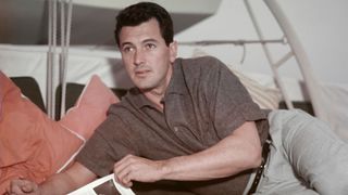 Rock Hudson laying down with a book