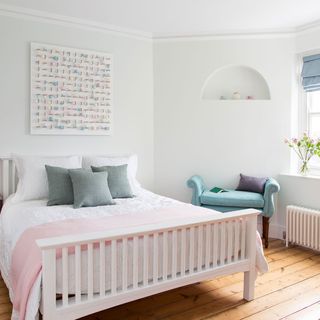 white bedroom with wooden flooring and blue couch with cushion