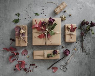 Presents wrapped in brown paper and string, decorated with festive flowers and foliage