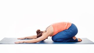 A woman doing childs pose on a yoga mat