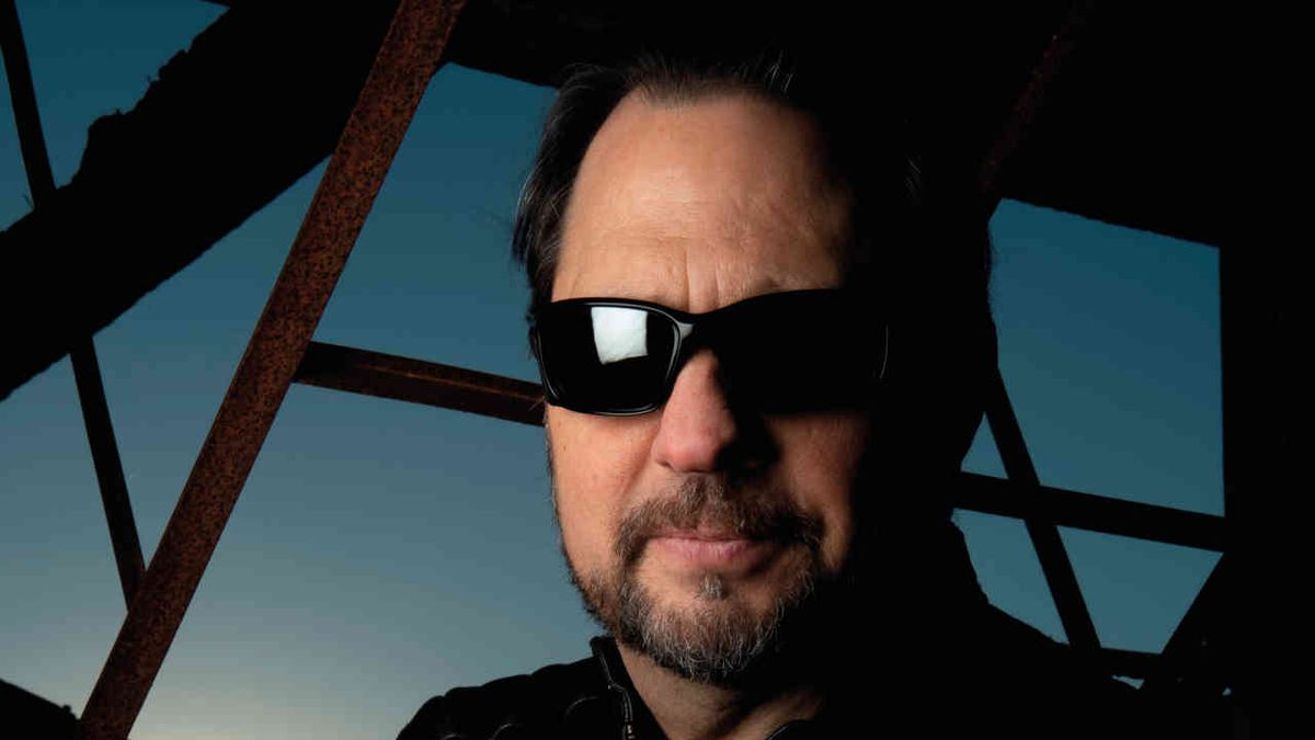 Dave Lombardo wearing sunglasses against a blue background