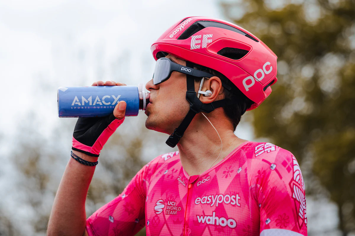 A cyclist in EF Education Easypost kit drinks Amacx chery juice