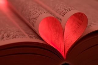 A heart shape made with the pages of a book, with a red glow.