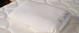 The image shows the white Purple GridCloud pillow placed on top of a on a white mattress 