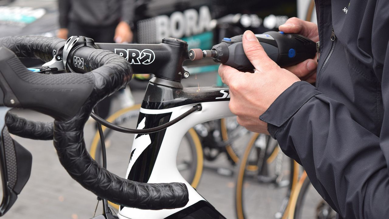A Bora-Hansgrohe mechanic files down stem bolts the day before the race