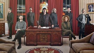 Laibach posed around the desk of an Oval Office-style room 