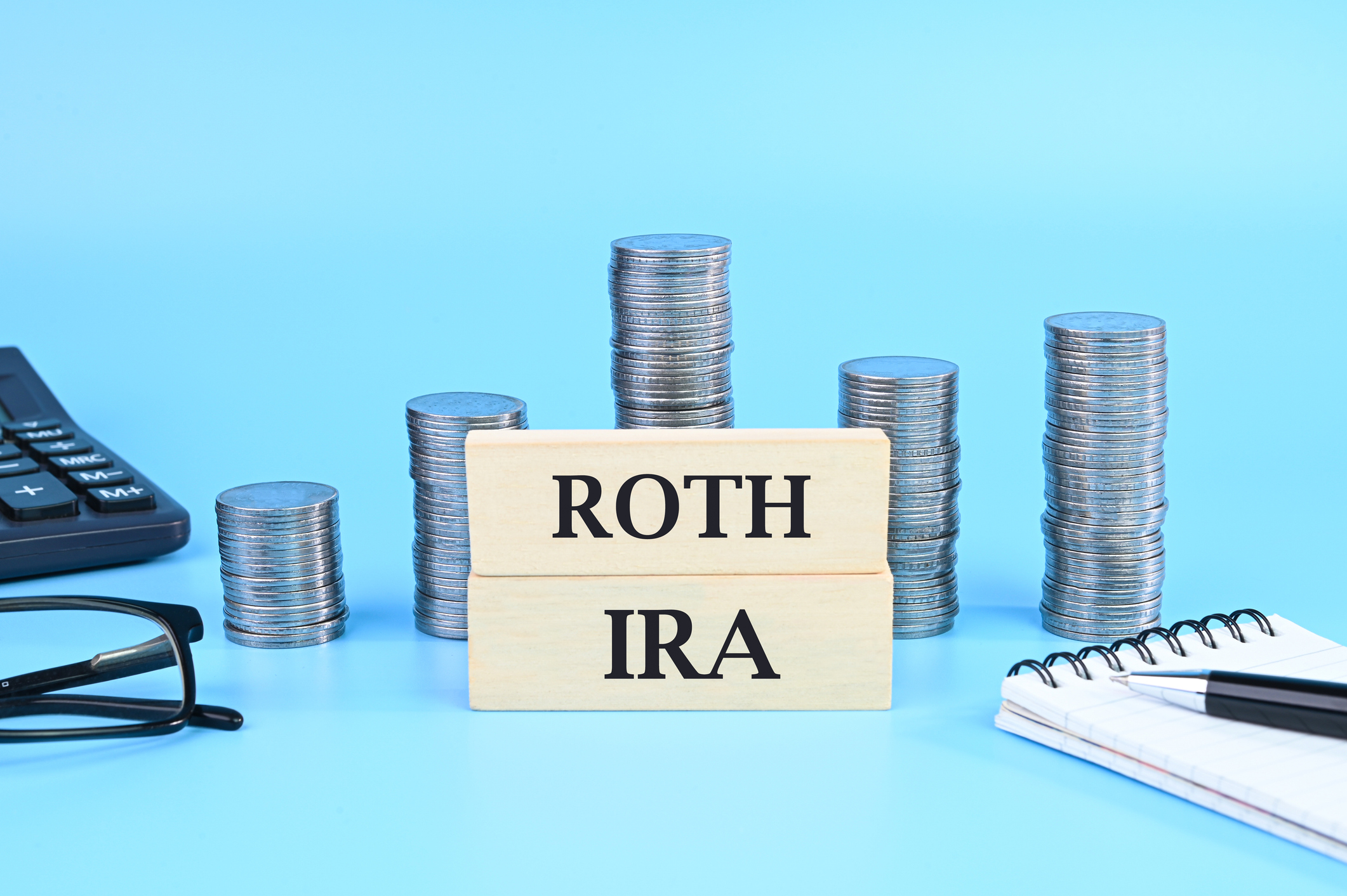 &#039;roth ira&#039; on wooden blocks with stacks of coins and various office supplies