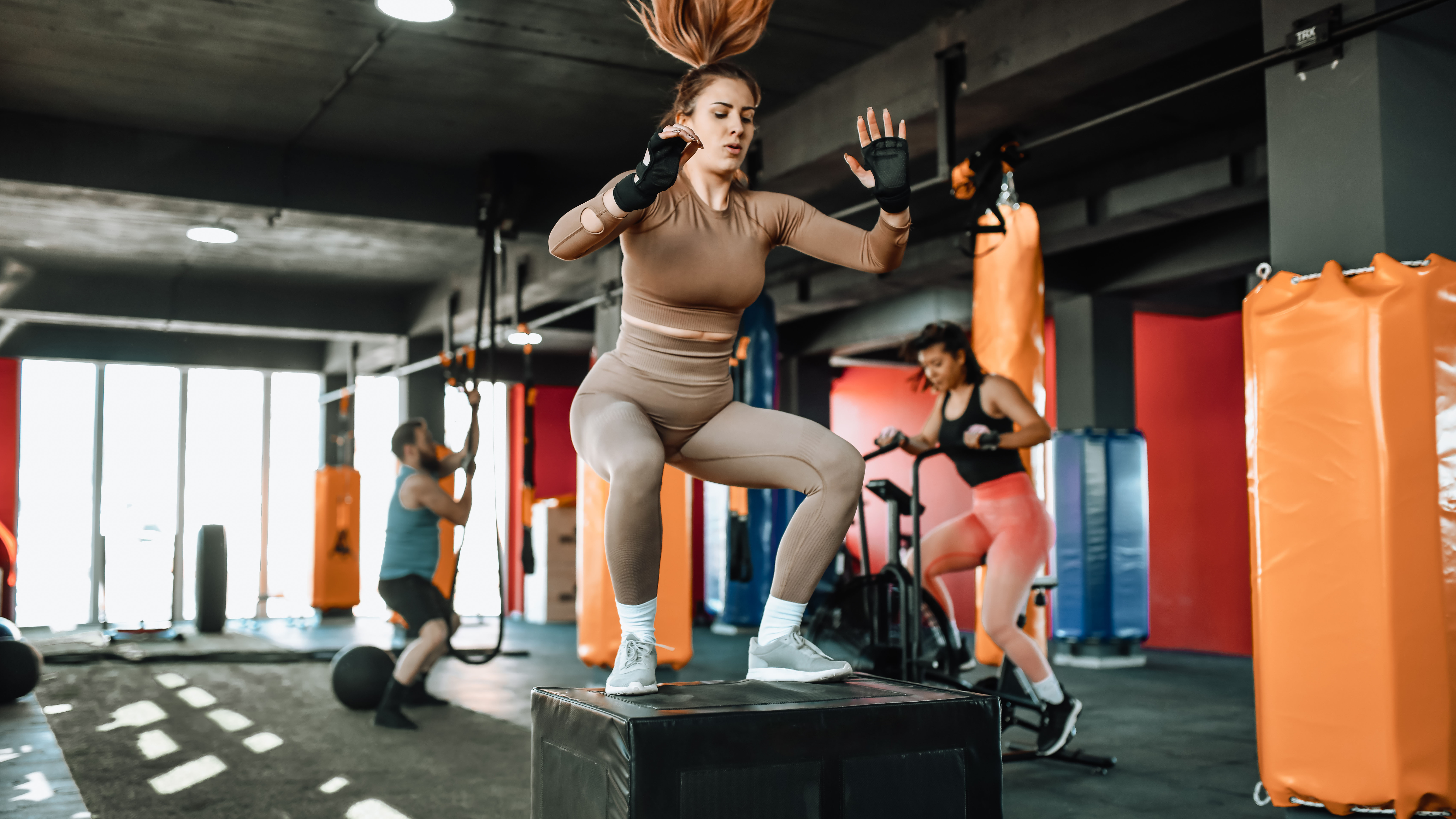 Mujer haciendo entrenamiento funcional saltando sobre la caja en el gimnasio