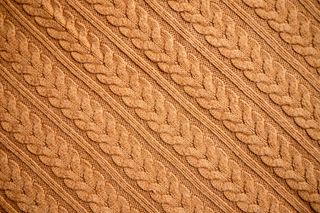 A close up of the texture of an orange knitted jumper.