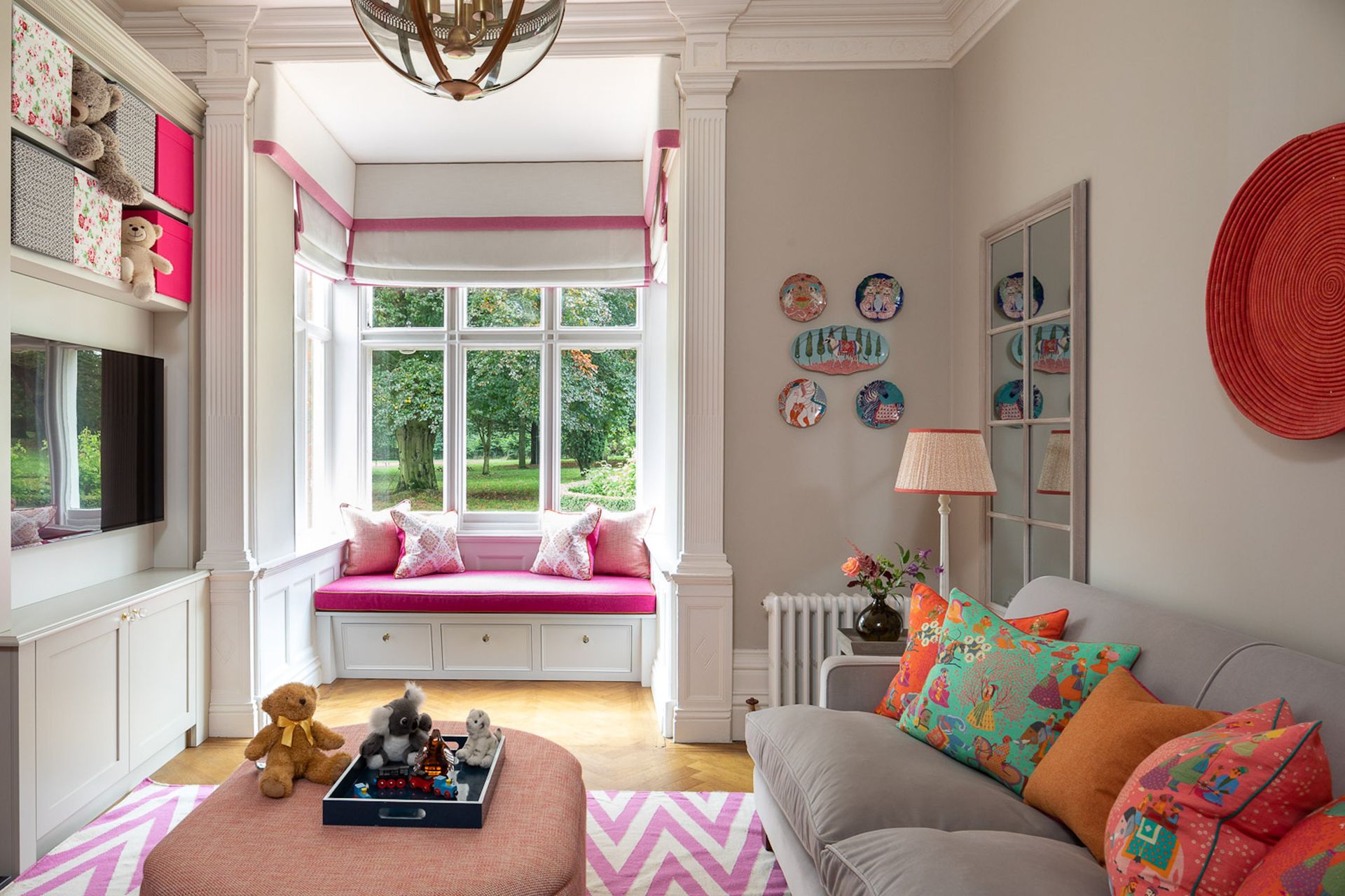 Family living room in neutral with pink accents with sofa, footstool, windowseat and rug