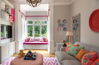Family living room in neutral with pink accents with sofa, footstool, windowseat and rug