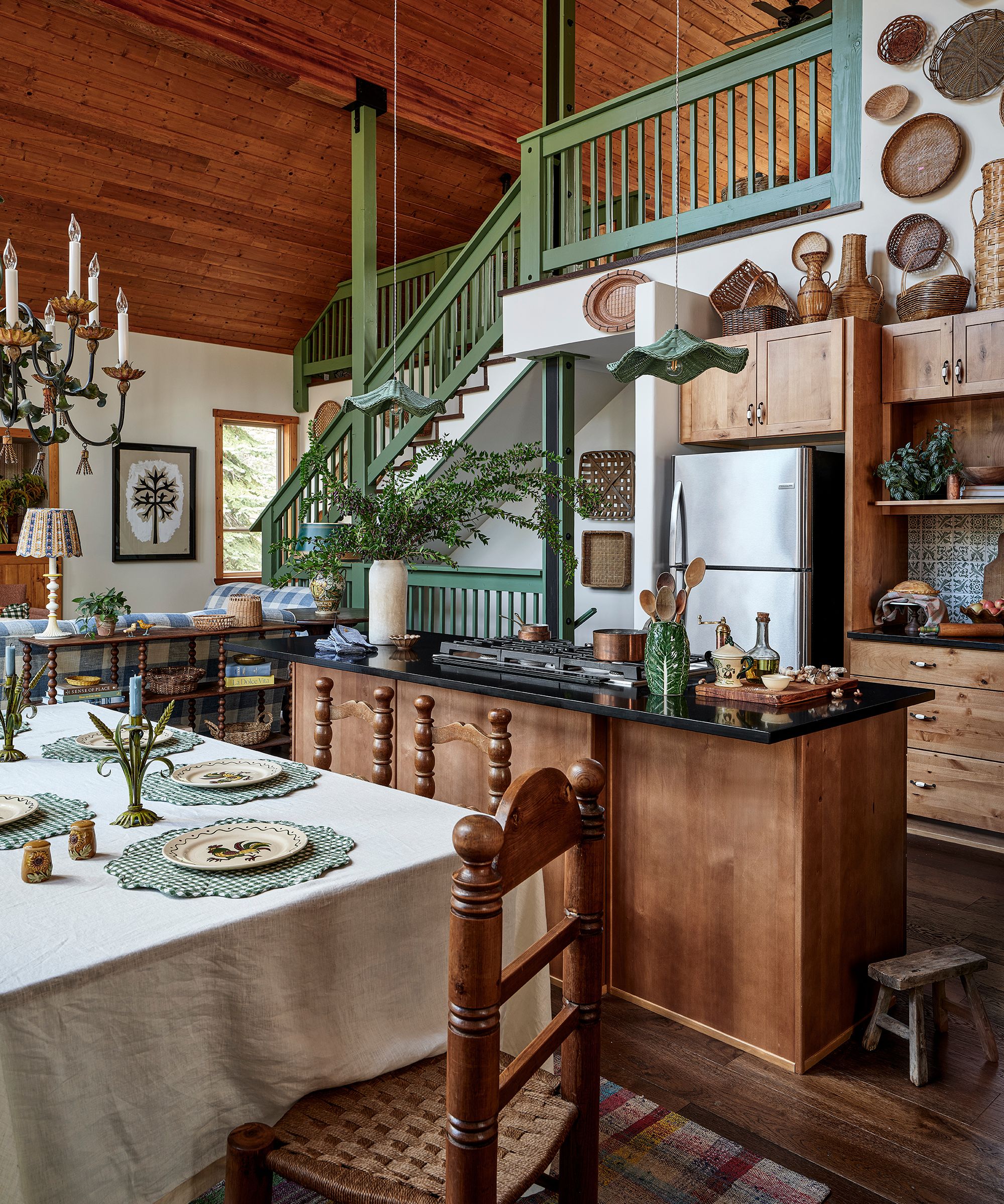 a vaulted wooden ski chalet great room with a green staircase, wooden kitchen and a dining area
