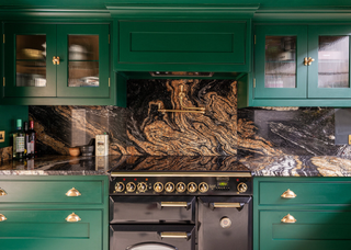 Green kitchen cabinets with swirled marble counter and matching backsplash