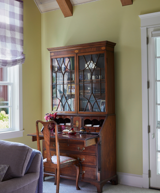 A wooden vintage hutch against a light green wall.