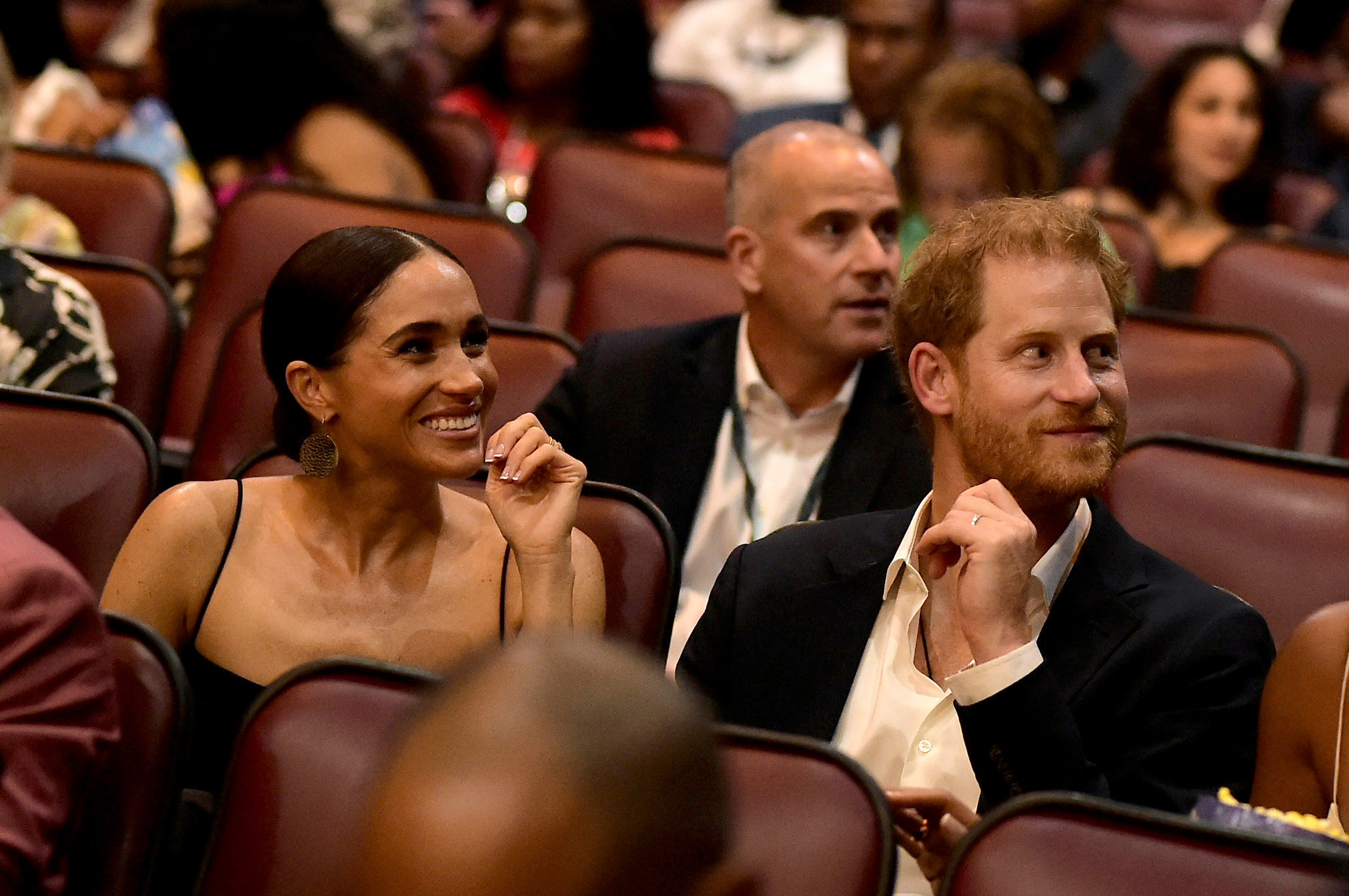 Prince Harry and Meghan Markle sitting in seats at a movie