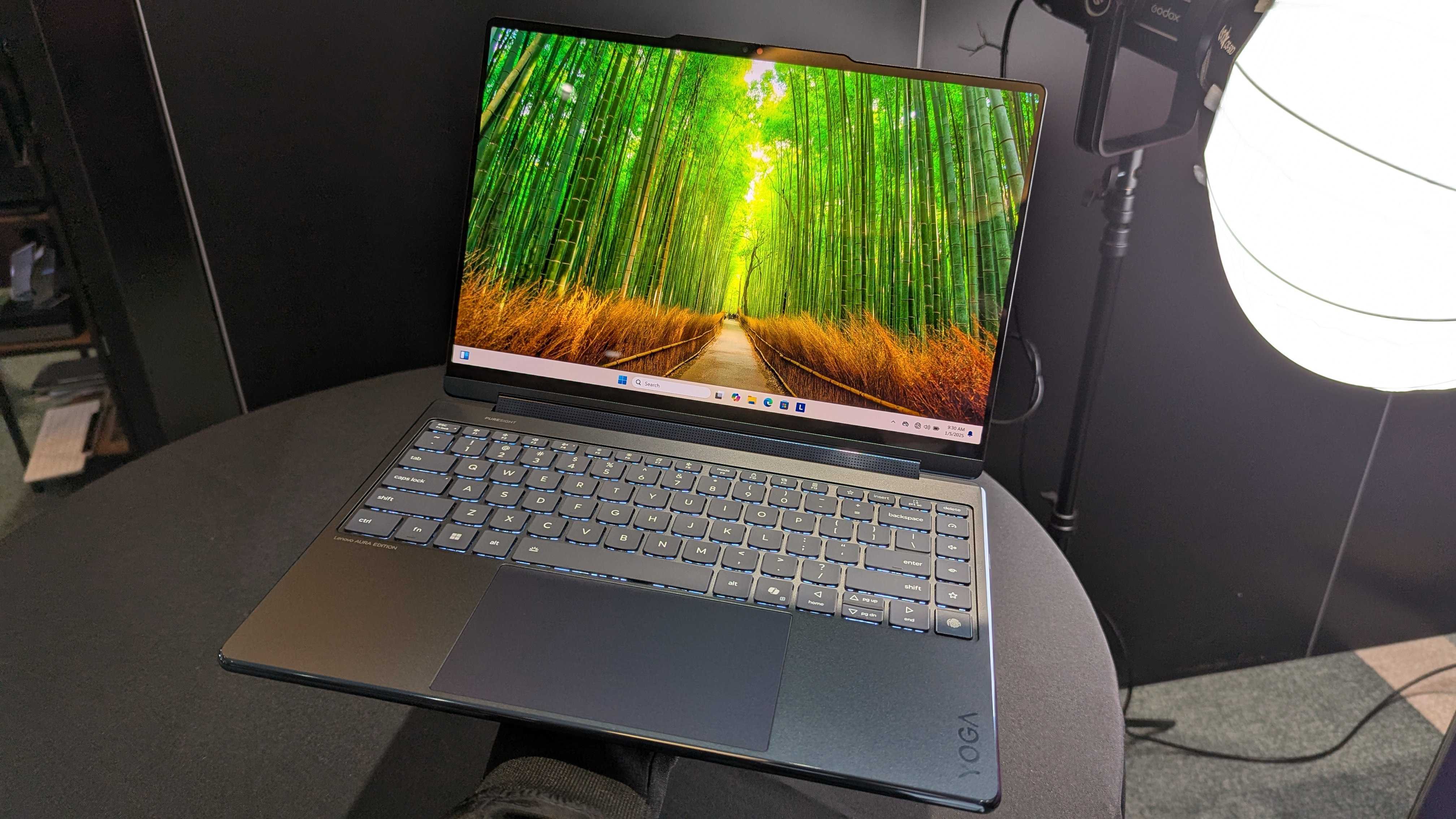 The Lenovo Yoga 9i 2-in-1 14 (Gen 10) Aura Edition held in the hand with its display open.