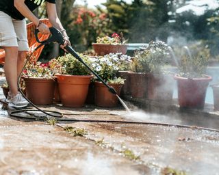 Person cleaning the poolside with high pressure water cleaning